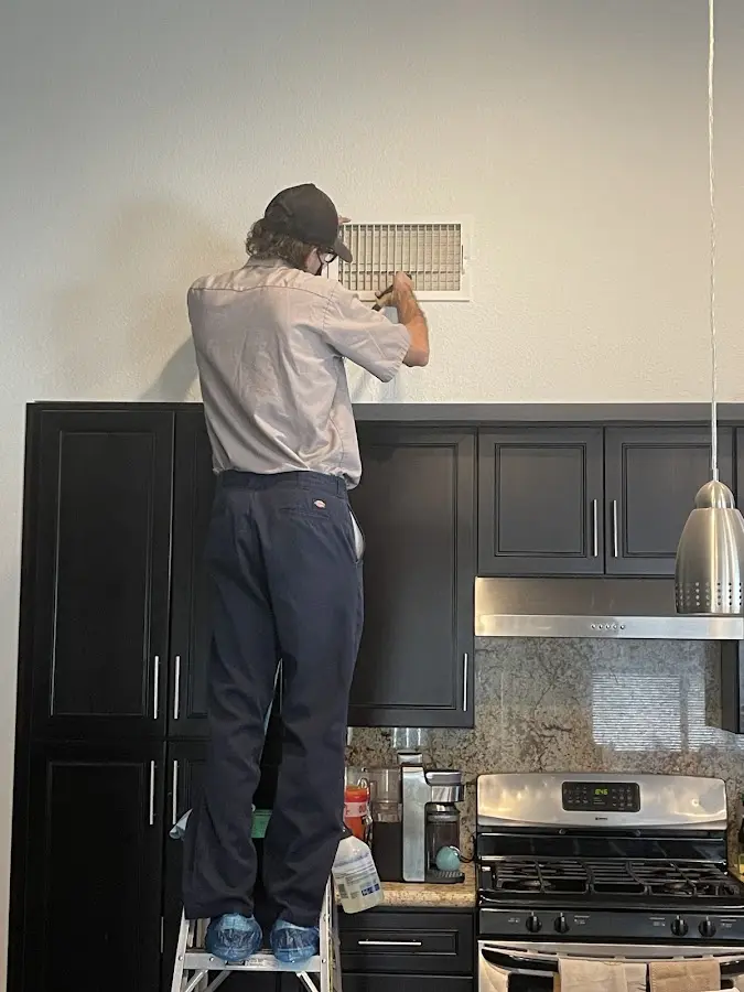 Technician inspecting an air vent during HVAC service in Texas City